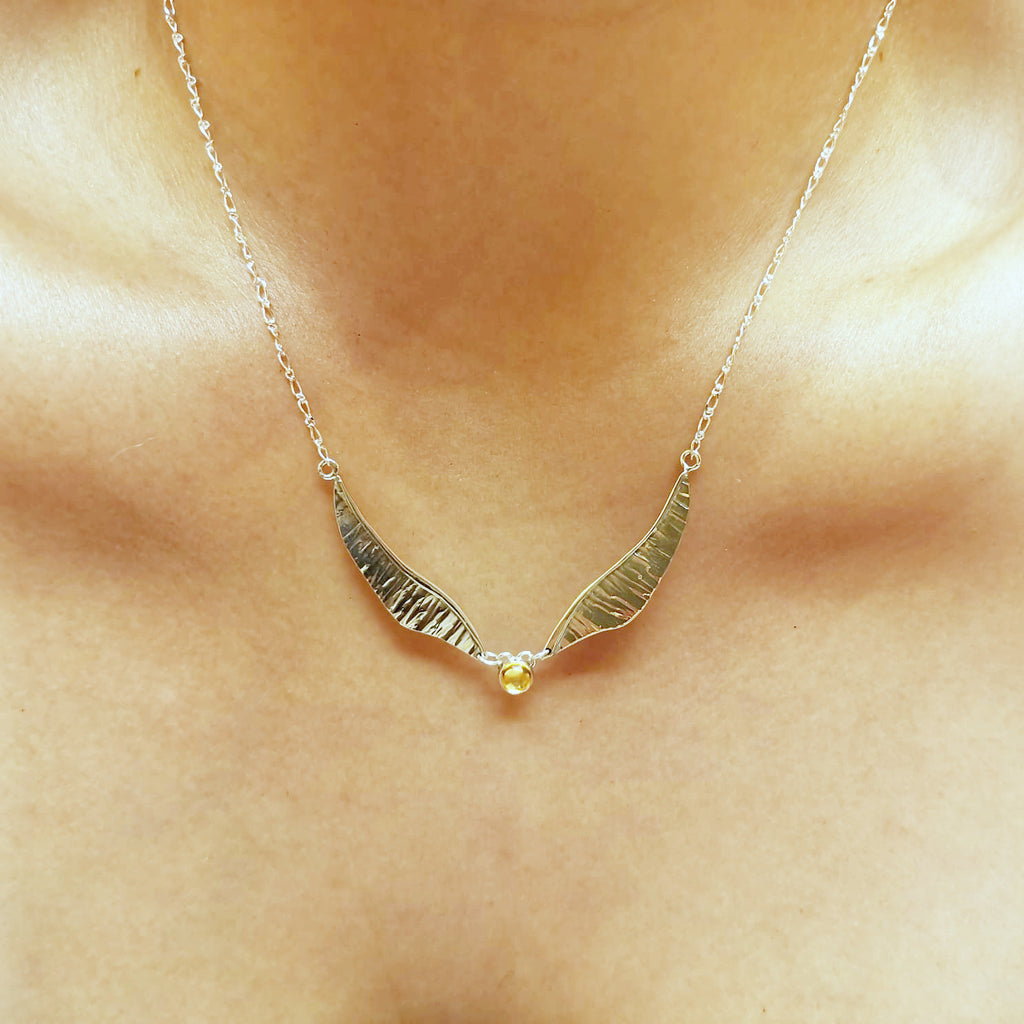 Golden wing necklace worn with long pendant and silver chain