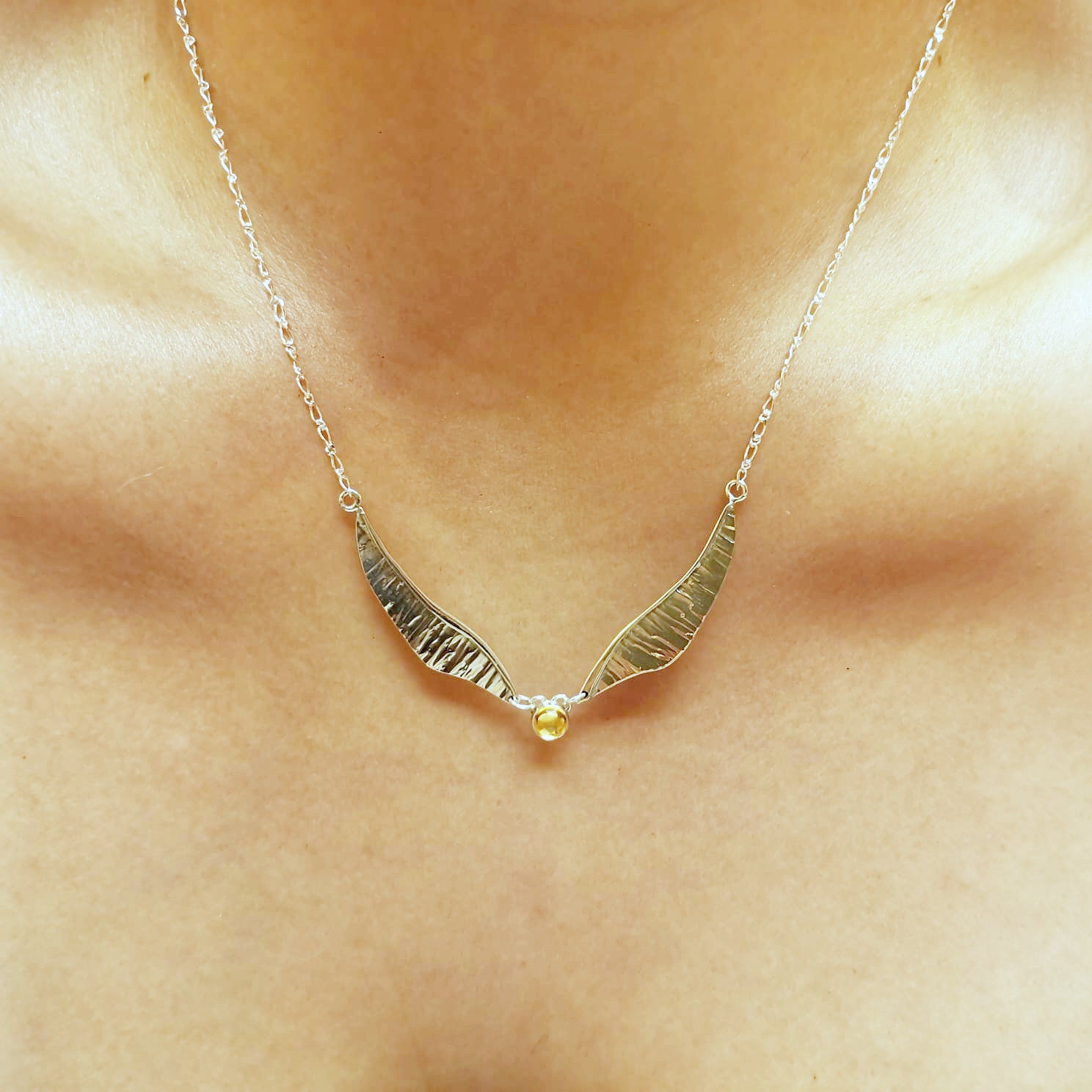 Golden wing necklace worn with long pendant and silver chain