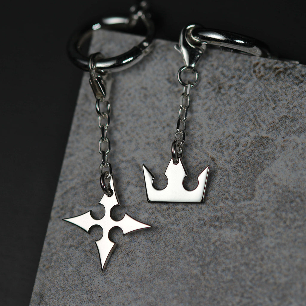 Detail of Korona chain earrings showing crown and cross charms linked by a fine chain