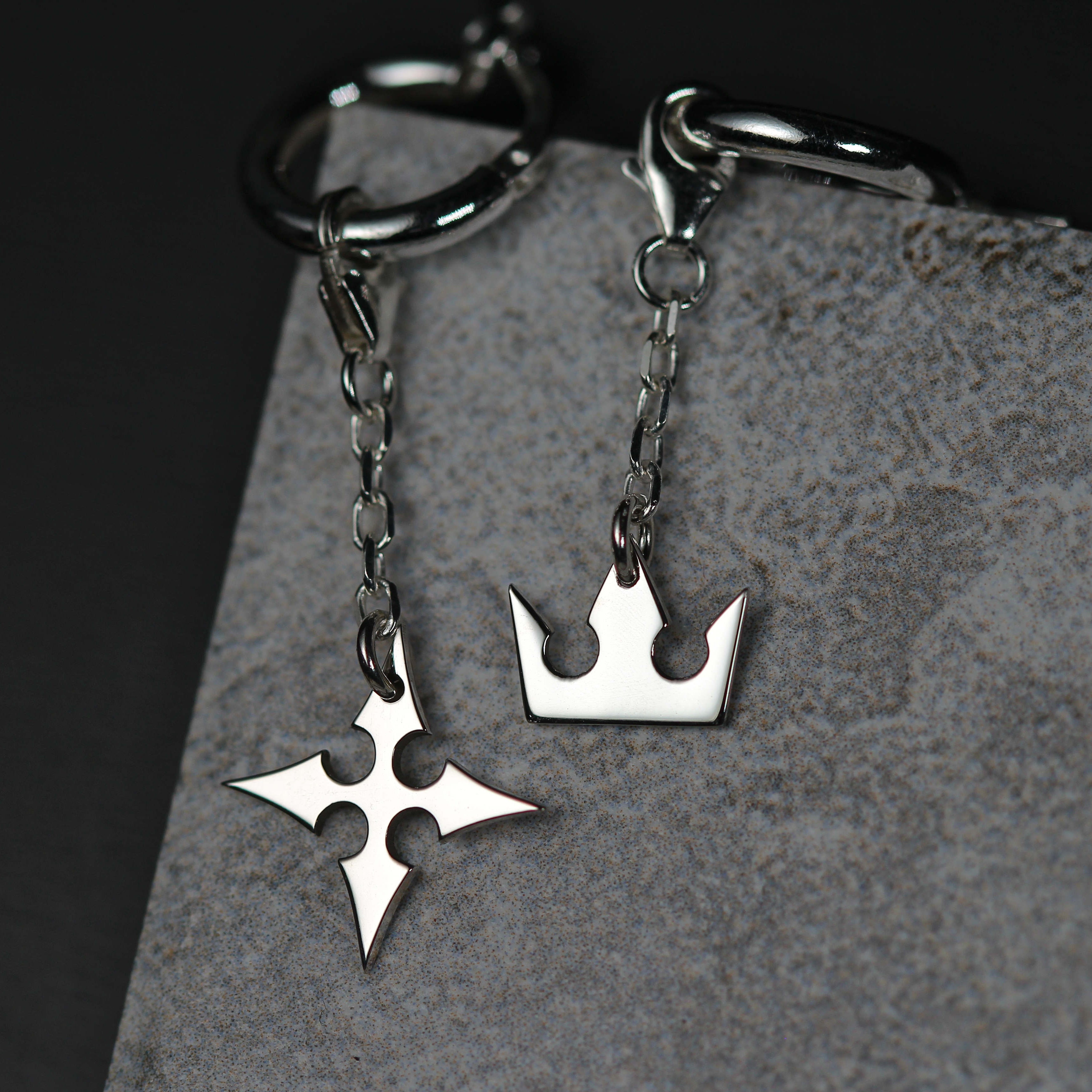 Detail of Korona chain earrings showing crown and cross charms linked by a fine chain