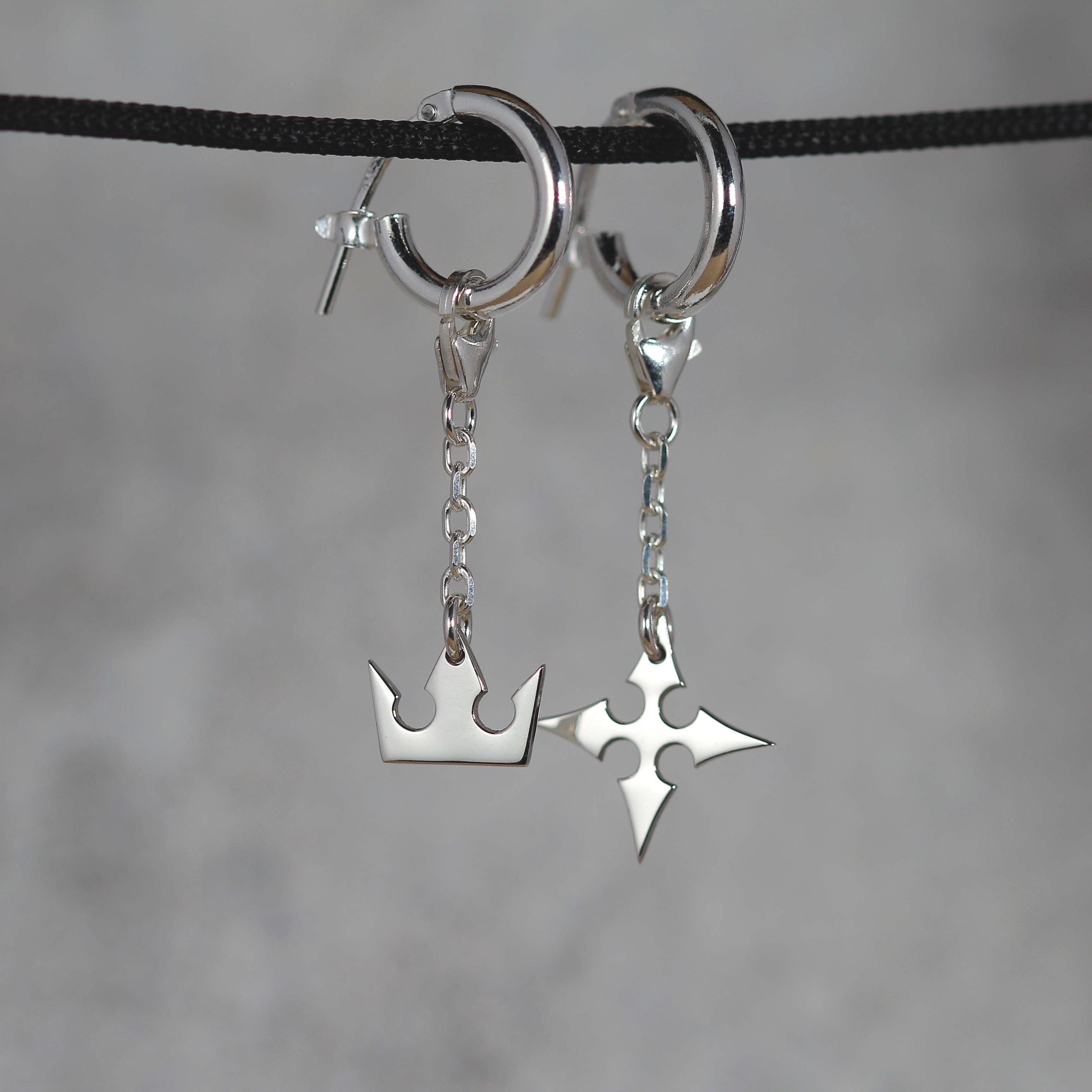 Full view of Korona chain earrings in sterling silver with crown and cross symbols and chain detail