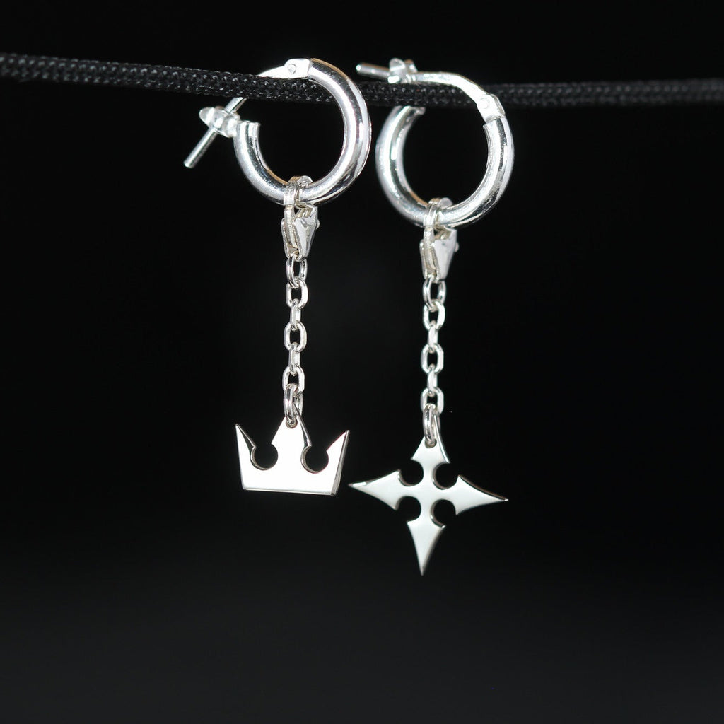 Korona chain earrings in sterling silver with crown and cross symbols connected by a delicate chain