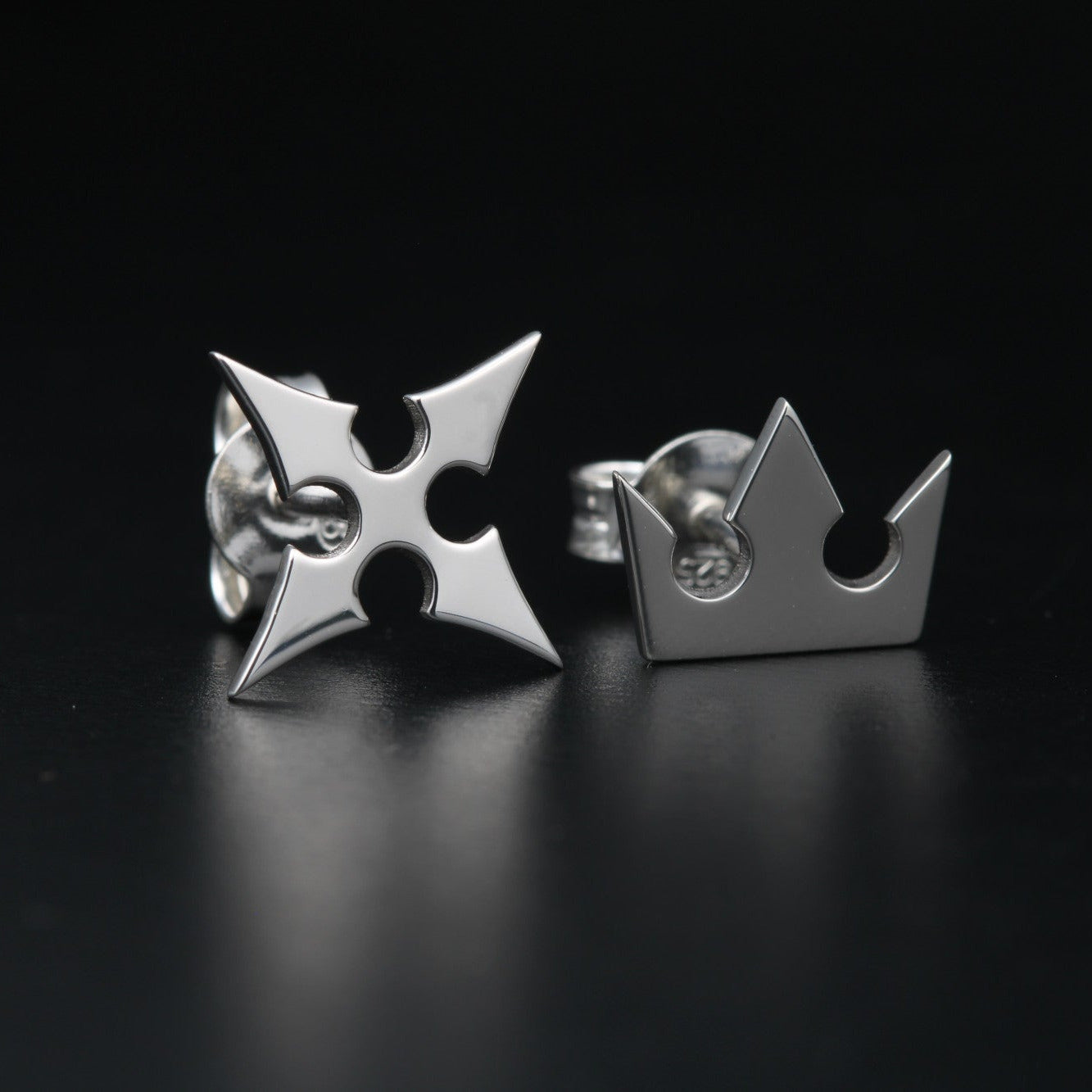 Detail of Korona stud earrings showing crown and cross symbols in sterling silver