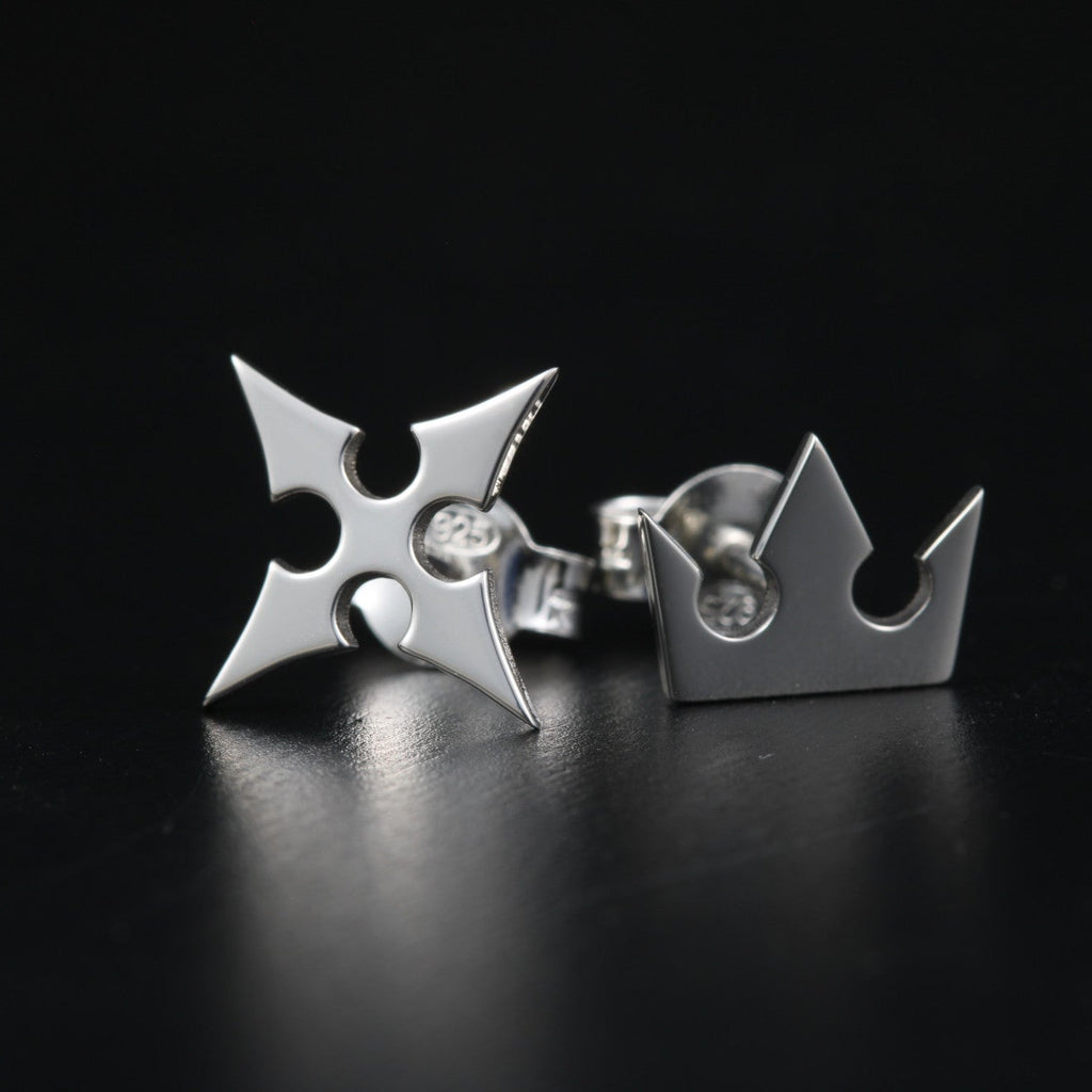 Full view of Korona stud earrings in sterling silver with crown and cross symbols representing light and darkness