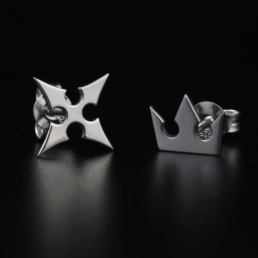 Korona stud earrings in sterling silver with crown and cross symbols representing light and darkness